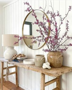 a table with vases and a mirror on top of it next to a lamp