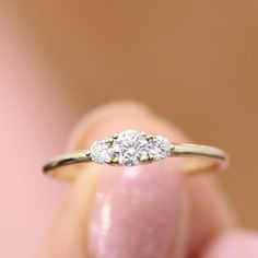 a woman's hand holding a three stone diamond ring