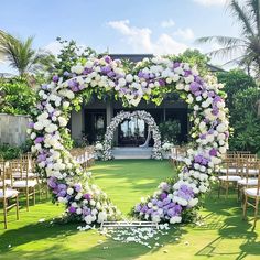 a heart shaped floral arrangement in the middle of an outdoor wedding ceremony area with white and purple flowers