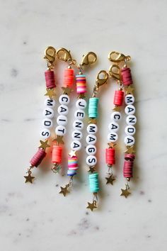 several charms with words and stars hanging from them on a marble counter top in the shape of letters