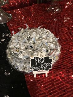 a bowl filled with silver foil covered candies on top of a red table cloth