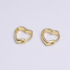 pair of gold - plated heart shaped clip earrings on white background, top view