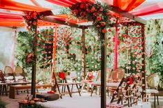 an outdoor area with tables, chairs and flowers on the ceiling is decorated in red and orange colors