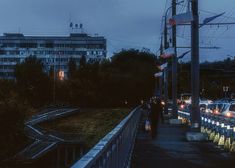 cars are parked on the side of a road at night time with buildings in the background