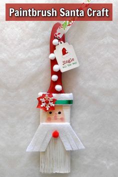 a santa claus ornament hanging from a red and white pole with the words paintbrush santa craft on it