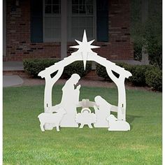 a white nativity scene in the grass with a star above it and a manger