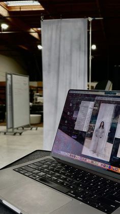 an open laptop computer sitting on top of a table in front of a white wall