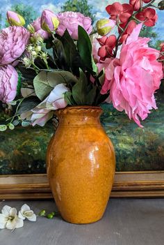 a vase filled with lots of pink and red flowers sitting on top of a table