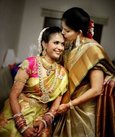 two women standing next to each other wearing different colored sari and jewelry on their heads