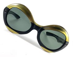 Vintage Sunglasses FRANCE Gold and Black These absolutely fabulous vintage sunglasses were made in France most likely in the 1970s. These large and dramatic oversized bubble like shaped sunglasses are glossy black with a metallic gold top and bottom bands across the front. The sahpe is a unique round oval with really cool angles around he lenses the lenses are green and seem to be plastic. Inside one bow, it is emossed with the the word FRANCE in gold. Measures 6" across x 2 3/8". Each bow is measures 5" long. These glasses are in good vintage condition and only show light wear for age. There is a bit of marking on the gold surface and very minor light scuffs on the frame and I see a small scratch on the lens. Channel your inner Jackie OHH! These marvelous vintage sunglasses are very rare, Vintage Eye Glasses, Vintage Ring Box, Shaped Sunglasses, Cameo Necklace, Vintage Eyewear, Gold Top, Absolutely Fabulous, Vintage Sunglasses, Mesh Bag