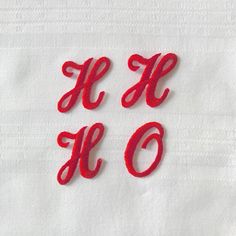 three red letters are placed on a white cloth with the letter h and o written in cursive font