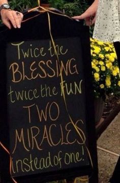 a woman holding a sign that says twice the blessing twice the fun two muracs instead one