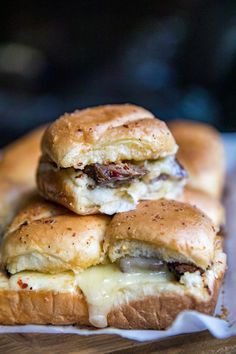 three sandwiches stacked on top of each other with cheese and meat in between the buns