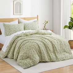 a bed with green and white bedspread in a room next to a potted plant