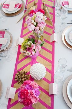 the table is set with pink flowers and gold place settings for an elegant dinner party