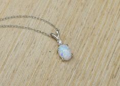 "Gorgeous pairing of a white opal and CZ accent gemstone. The gemstones are handset into a sterling silver pendant and hung from a sterling silver chain. This white opal has amazing flashes of color when it catches the light. The resulting necklace is stunning yet simple, a truly elegant necklace! The necklace ships in a lovely gift box ready to give as a gift or keep for yourself! Pictured with cubic zirconia accent stone color: \"White / Clear - April\" Setting Material - 925 Sterling Silver C White Opal Birthstone Jewelry, White Oval Opal Necklace, White Opal Anniversary Necklace, White Opal Pendant Jewelry, White Opal Gemstone Necklace, White Sterling Silver Birthstone Necklace, Opal Necklace Silver, Elegant Necklace, Necklace White