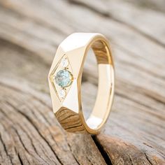 a yellow gold ring with an aquamarine stone in the center on a wooden surface