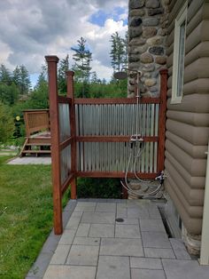 an outdoor shower in front of a house with stone steps and green grass on the side