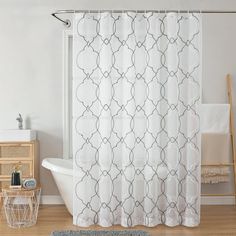 a bathroom with a shower curtain, rug and bathtub on the wooden flooring