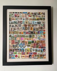 a black frame with many different postage stamps on it and a white wall in the background