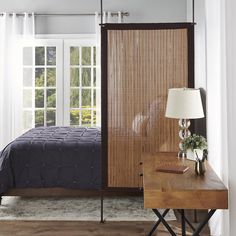 a bed sitting next to a wooden table with a lamp on it's side