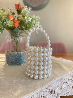 a vase filled with flowers next to a white purse on top of a lace table cloth