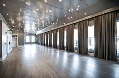 an empty room with wooden floors and large windows in the center is lit by recessed lights