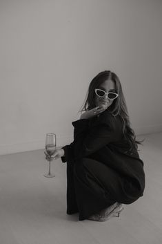 a woman sitting on the floor with a glass of wine in front of her face