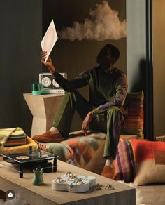 a man sitting on top of a couch holding a paper