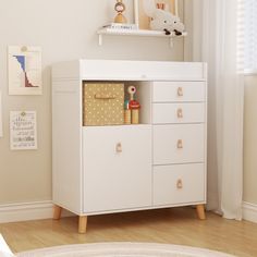 a white cabinet with drawers and pictures on the wall above it in a child's room