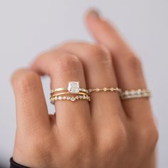 a woman's hand with two rings on her fingers and one ring in the middle