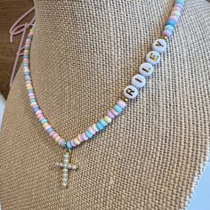 "Your little one will love to accessorize with this cute cross charm necklace! It is made with pastel seed beads and a little faux pearl charm. It will make any outfit more special! Personalize it with any name! This makes a great Easter or Christmas Gift!  This 15\" stretchy necklace fits right over your head so it's easy to put on- no clasps needed.  🤍 Please check all selections and spelling prior to check out. Our custom jewelry is made to order so all sales are final. 🤍 The necklace is beautifully packaged and ready to gift. Receipts are never included. If you want to include a special note, please let me know in the comments. 🤍 Please be advised small parts can be a choking hazard and children shouldn't wear jewelry unsupervised. San Diego Bead Shop assumes no responsibility for t Toddler Easter Gifts, Pearl Cross Necklace, Cross Charm Necklace, Clay Bead Necklace, Dream Bracelet, Cute Cross, Girl Necklace, Christian Necklace