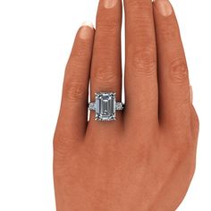 Emerald Cut Cocktail ring shown with a 14x10mm, 9.00 ct. emerald cut colorless simulated diamond and (2) 4mm round colorless simulated diamonds, .50 ct. Band width 2.2mm. Solid 925 Silver9.50 carat total weight. *Sterling Silver is Rhodium dipped to reduce tarnishing. Rhodium is a very strong metal that creates a protective layer over the sterling silver, making it more resistant to tarnishing.*Custom made at the time of order. Octagon Emerald Ring With Diamond Accents, Silver Emerald Baguette Cut Jewelry, Octagonal Emerald Ring With Diamond Accents For Formal Events, Octagon Emerald Ring With Diamond Accents For Formal Events, Emerald Jewelry With Brilliant Cut For Proposal, Brilliant Cut Emerald Jewelry For Proposal, Formal Octagon Emerald Ring With Diamond Accents, Timeless Diamond White Jewelry For Proposal, Octagon Platinum Emerald Ring As Gift