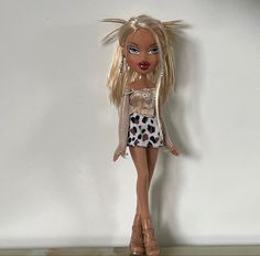 a doll with blonde hair and leopard print dress standing in front of a white wall