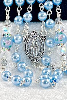 Austrian Crystal pearls make this Heavenly sky blue rosary perfect for a bridal bouquet or any special gift or occasion. If you are looking for Swarovski pearls, look no further! I use these interchangeably with my Swarovski light blue pearls and they match perfectly. They're the perfect substitute since Swarovski exited the market. The crucifix and centerpiece of the Miraculous Medal are both die cast oxidized silver and made in Italy. It can be personalized with any name 10 letters or less, an Blue Spiritual Jewelry For Wedding, Blue Spiritual Jewelry For Weddings, Light Blue Round Beads Jewelry For Wedding, Blue Spiritual Jewelry For First Communion, Heavenly Sky, Decades Of The Rosary, Blue Bridal Bouquet, Baby Baptism Gifts, Blue Rosary