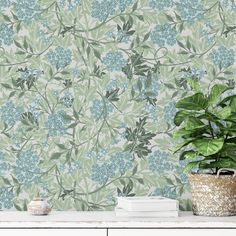 a potted plant sitting on top of a white table next to a wall paper