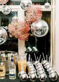 a table topped with lots of silver cups filled with drinks and desserts covered in disco balls