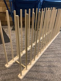 a row of white poles sitting on top of a carpeted floor next to blue chairs