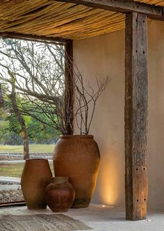 two large vases sitting under a wooden structure