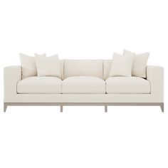 a white couch with four pillows on it's back and two side tables in front