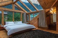 a large bed sitting inside of a bedroom next to a wooden wall covered in windows