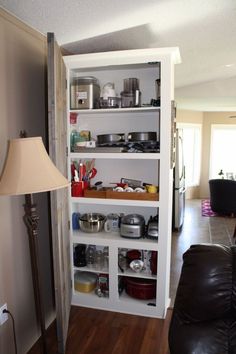 a living room filled with furniture and lots of clutter on top of the shelves