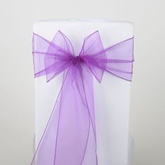 a white present box with purple ribbon and bow