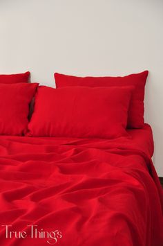 a bed with red sheets and pillows on it