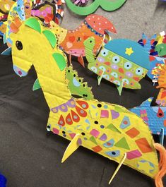 several colorful paper animals are on the ground next to each other, with one horse in the middle