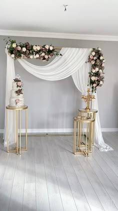 a white and gold wedding arch with flowers on the top is set up for a ceremony