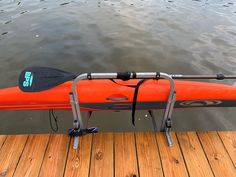 an orange kayak sitting on top of a wooden dock