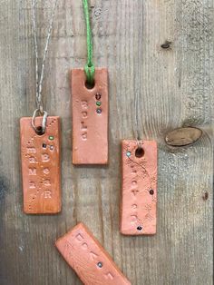 three pieces of clay are hanging on a wooden surface with green string attached to them