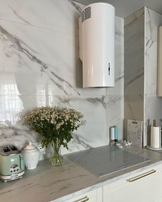 a kitchen with marble counter tops and white cabinets, including a small vase filled with baby's breath flowers