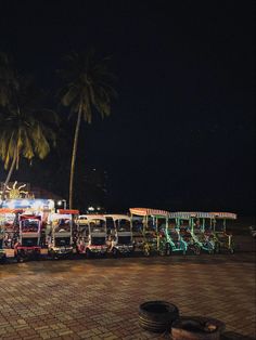 a row of buses parked next to each other on a brick road near palm trees